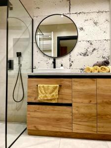 ein Bad mit einem Waschbecken und einem Spiegel in der Unterkunft Apartament Twierdza z widokiem na jezioro in Ostróda