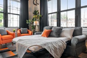 a living room with a couch and two orange chairs at Luxury Urban 1BR King Bed-Parking - Heart of Historic Germantown - Temple & LaSalle -105- Stay Long Term! in Philadelphia