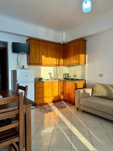 kuchnia z drewnianymi szafkami i kanapą w pokoju w obiekcie Fane's Apartments w mieście Himara