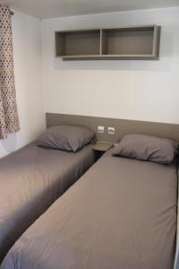 two beds sitting next to each other in a room at Mobil-home in Litteau