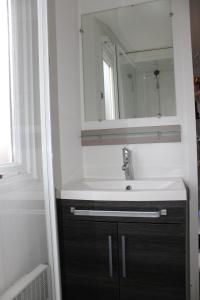 a bathroom with a sink and a mirror at Mobil-home in Litteau