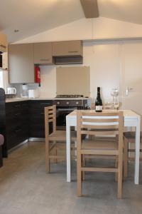 a kitchen with a table and chairs with a bottle of wine at Mobil-home in Litteau
