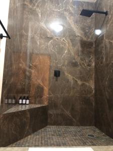 ein Badezimmer mit einer großen Marmordusche mit Flaschen auf dem Boden in der Unterkunft Tres Iguanas Apart Hotel - New, cozy & spacious flats, short walk to beach in Loreto