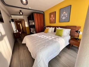 a bedroom with a large white bed with yellow walls at Hotel Olá Chapultepec in Guadalajara