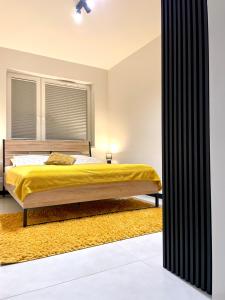 sypialnia z łóżkiem z żółtym kocem w obiekcie Apartament Twierdza z widokiem na jezioro w Ostródzie