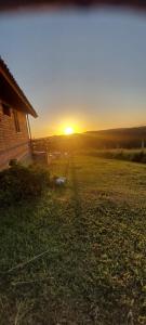 a sunset in a field next to a house at Chácara Bela Vista in Taquara