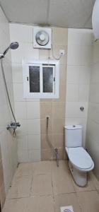 a bathroom with a toilet and a window and a shower at فندق إي دبليو جي الششة in Al Khansāk