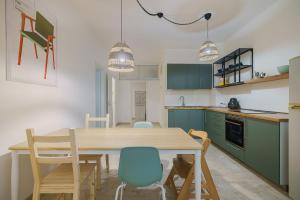 una cocina con armarios verdes y una mesa y sillas de madera. en Italianway - Mazara City Center Family Apartments, en Mazara del Vallo
