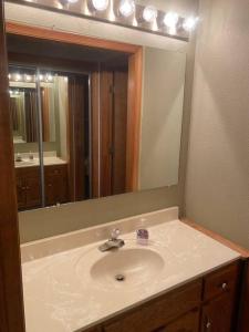 La salle de bains est pourvue d'un lavabo et d'un grand miroir. dans l'établissement LOZ Paradise Sleep 12-Bachelor/Bachelorette Party!, à Lac des Ozarks