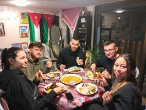 un grupo de personas sentadas alrededor de una mesa comiendo comida en The guset house, en Kerak