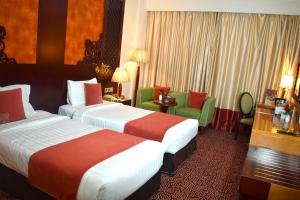 una habitación de hotel con 2 camas y sillas verdes en Dubai Grand Hotel by Fortune, Dubai Airport, en Dubái
