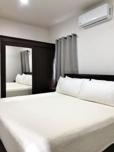 une chambre avec un lit blanc et un miroir dans l'établissement Samudra Villas 2, à San Pedro