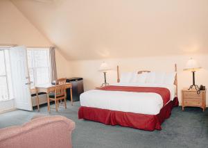 1 dormitorio con cama, escritorio y silla en Ceilidh Country Lodge, en Baddeck