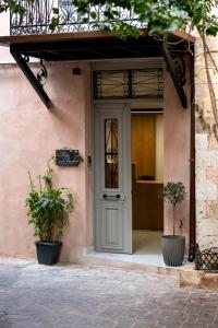 einer Haustür eines Hauses mit zwei Topfpflanzen in der Unterkunft Porto Vecchio in Chania