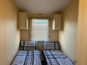 twee bedden in een kleine kamer met een raam bij CaSa VistA - Holiday Home On The Beach in Clacton-on-Sea