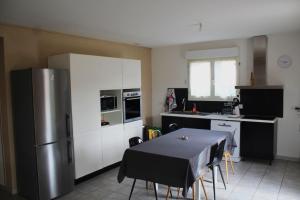 eine Küche mit Tisch und Edelstahlkühlschrank in der Unterkunft Maison avec jacuzzi et vue sur les penitents in Les Mées