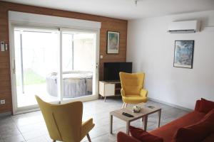 ein Wohnzimmer mit einem Sofa, Stühlen und einem TV in der Unterkunft Maison avec jacuzzi et vue sur les penitents in Les Mées