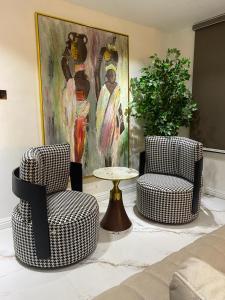 two chairs and a table in a living room with a painting at PROOF RESIDENCE in Lekki