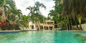 una piscina di fronte a una casa con palme di "Villa Infinito"Bani's Exclusive Beachside Mansion a La Noria