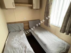 two beds in a small room with a window at Aloha - Cosy 2 Bed Close to Venue at Seal Bay, Selsey in Chichester