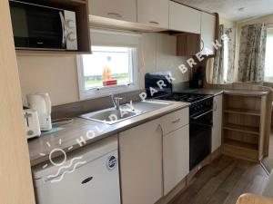 a small kitchen with a sink and a stove at Aloha - Cosy 2 Bed Close to Venue at Seal Bay, Selsey in Chichester