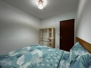 a bedroom with a bed with a blue comforter at Apto bem localizado est de Ribamar ao lado do shopping in São-José-do-Ribamar