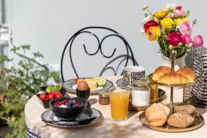 a table with breakfast foods and a vase of flowers at MEDLEY in Athens