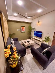 a living room with blue couches and a flat screen tv at Islamabad Oasis Residences in Islamabad