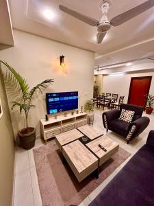 sala de estar con TV, sofá y mesa en Islamabad Oasis Residences, en Islamabad
