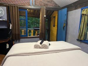 a bed with towels on it with a window at Pousada Lua Bonita in Nova Lima