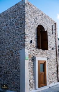 een bakstenen gebouw met een deur en een raam bij SKINOS rooms and apartment in Pyrgi