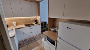 a small kitchen with white cabinets and a refrigerator at Lesíček in Vysoké Tatry