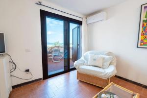 a living room with a chair and a sliding glass door at Marinella-Porto Rotondo, Accesso Diretto sulla SPIAGGIA in Porto Rotondo