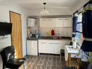 una pequeña cocina con armarios blancos, mesa y microondas en Rincón Avellaneda in 