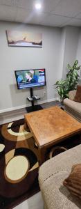 New Stylish 2-Bedroom Basement Suite في وينيبيغ: غرفة معيشة مع طاولة وتلفزيون بشاشة مسطحة