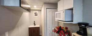 a small kitchen with a microwave and a sink at New Stylish 2-Bedroom Basement Suite in Winnipeg