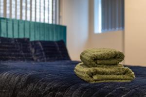 a pile of green towels sitting on top of a bed at MARSH lux 3 in Manchester