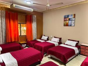 three beds in a room with red sheets at Al-Amer Hostel 1 in Aqaba