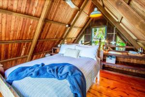 1 dormitorio con 1 cama en una cabaña de madera en The Gallery - Beach hideaway in stunning 1770, en Seventeen Seventy
