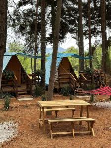 een picknicktafel en banken voor sommige tenten bij El descanso casa-hotel zacatlán in Zacatlán