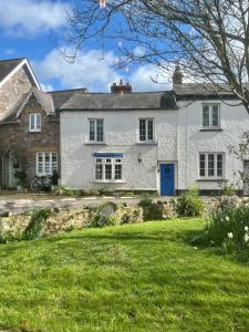 una casa blanca con una puerta azul en un patio en The Snuggery Cottage, en Taunton