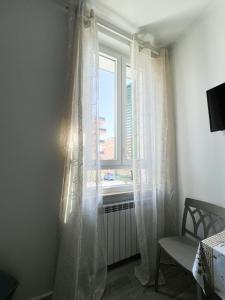 Cette chambre dispose d'une fenêtre avec des rideaux blancs. dans l'établissement B&B Rifugio San Francesco, à Lido di Ostia