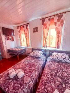 1 Schlafzimmer mit 2 Betten, einem Tisch und Fenstern in der Unterkunft Zielony Domek nad Biebrzą 