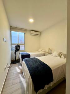 1 dormitorio con 2 camas y ventilador. en Espectacular apartamento en Barranquilla, en Puerto Colombia