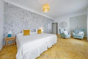 a bedroom with a large white bed and two blue chairs at Labreña Hotel in Los Caños de Meca