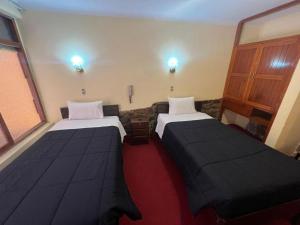 two beds in a room with a red carpet at HOSTAl HUAYNA HOUSE in Cusco