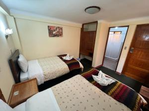 una habitación de hotel con 2 camas y una puerta en HOSTAl HUAYNA HOUSE, en Cusco