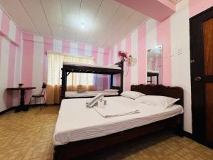 a bedroom with a bed in a room with pink and purple stripes at Duchess Sophia's Pension in Puerto Princesa City