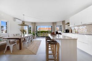 a white kitchen with a wooden table and chairs at Sunday Morning Guesthouse in Aljezur