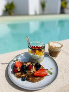 een bord met fruit en een pot yoghurt bij Sunday Morning Guesthouse in Aljezur